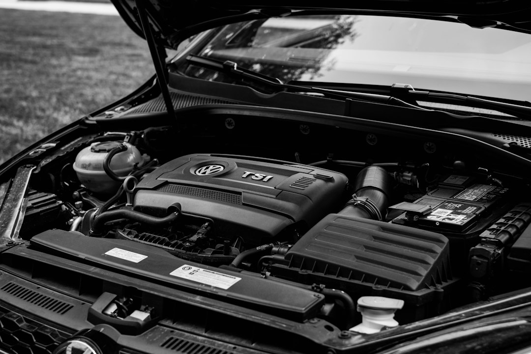 Car engine bay with the hood open, where the AC compressor and belt are located