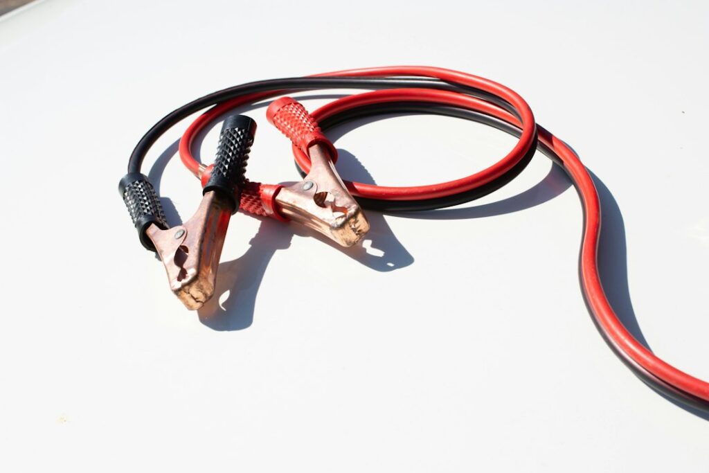 Red and black jumper cables used to jumpstart a dead car battery