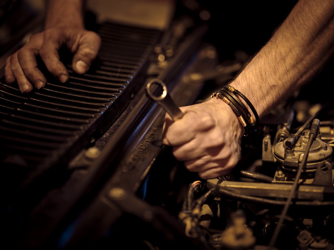 Hands working on a car engine with a wrench during a repair